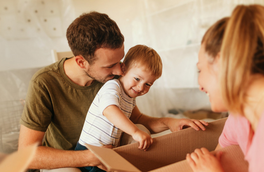 A woman and man holding young boy, packing boxes together